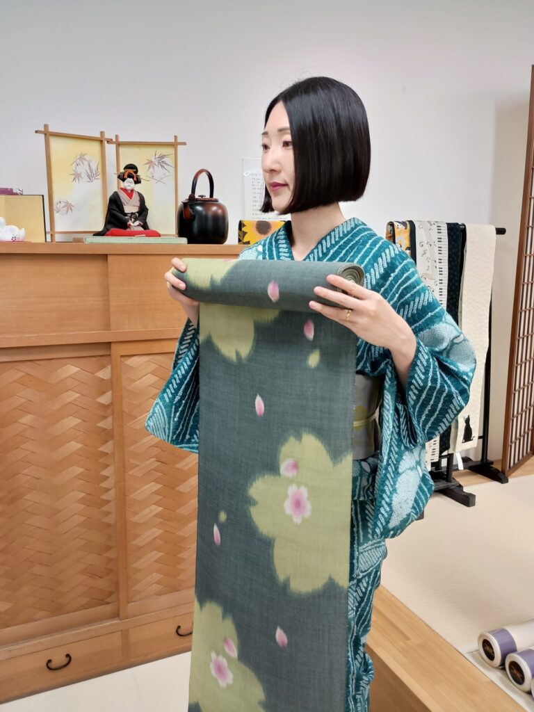 伊勢崎夏銘仙（ポーラ）の反物を体に当てる人